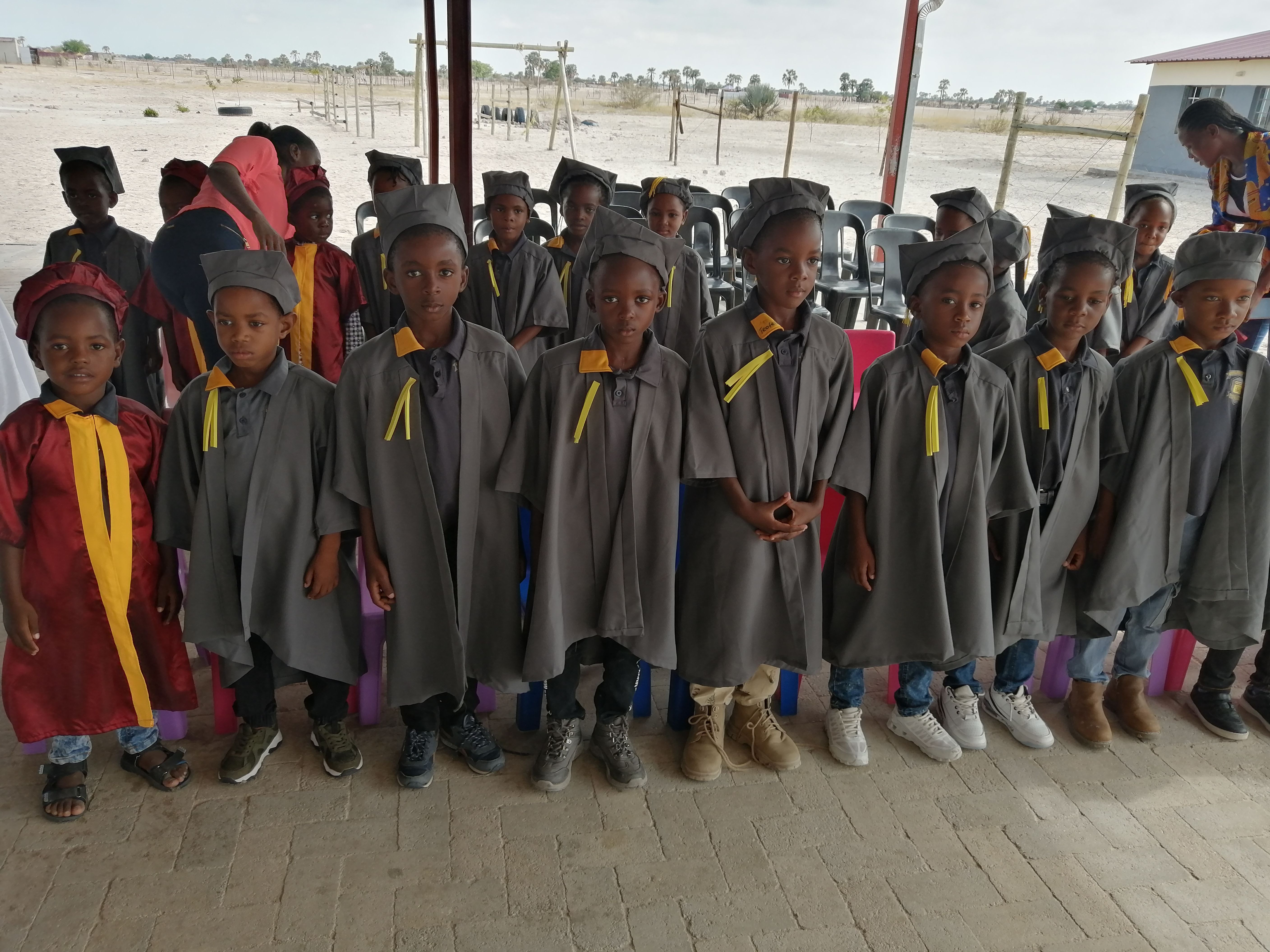 Students in graduation gowns and caps at pre-grade graduation ceremony