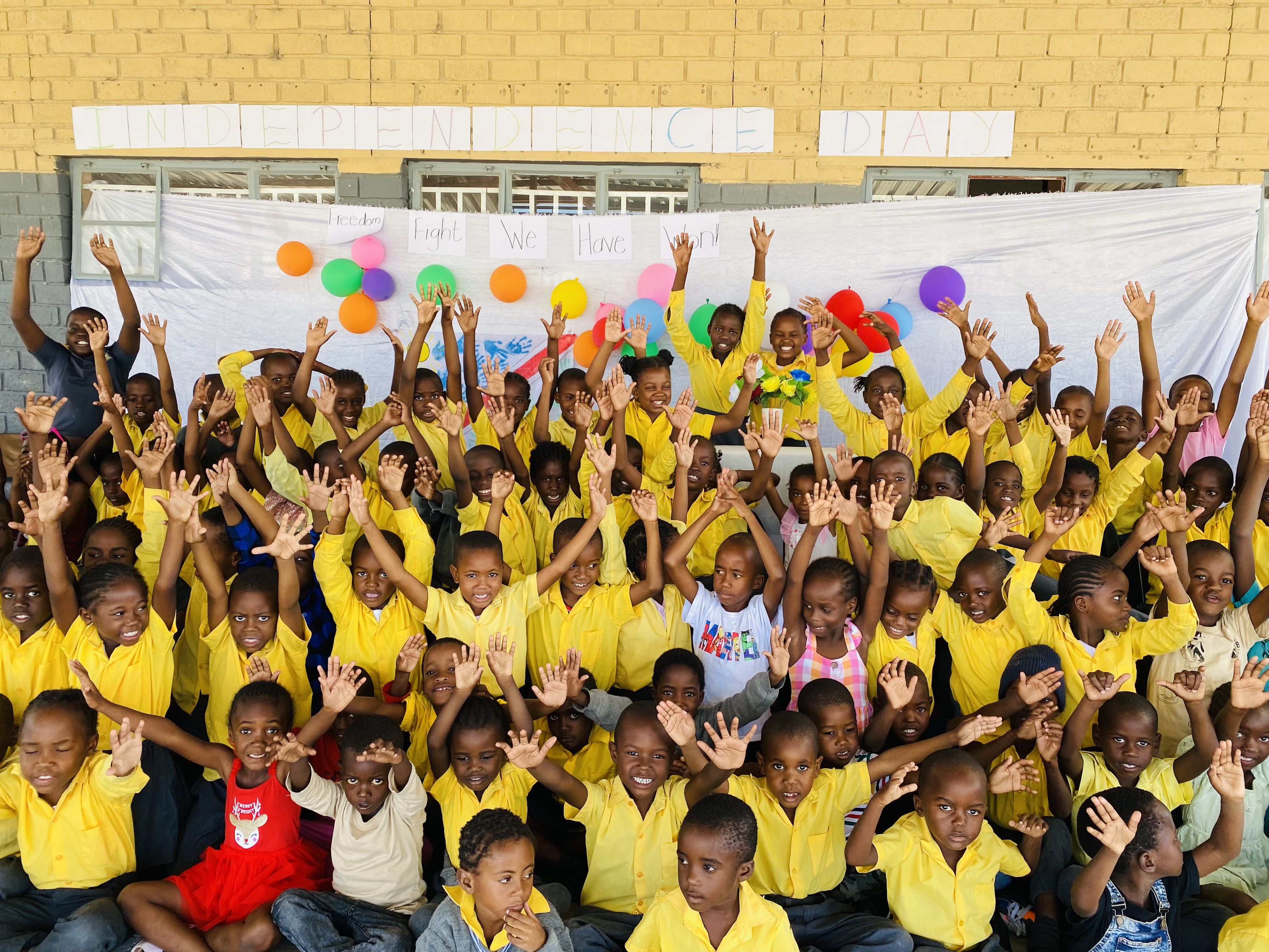Happy students waving at camera in school uniforms